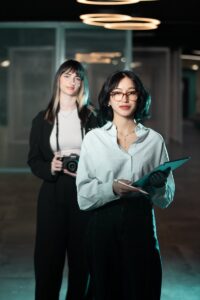 Deux femmes dans un cadre professionnel, l'une avec un appareil photo, symbolisant la créativité.